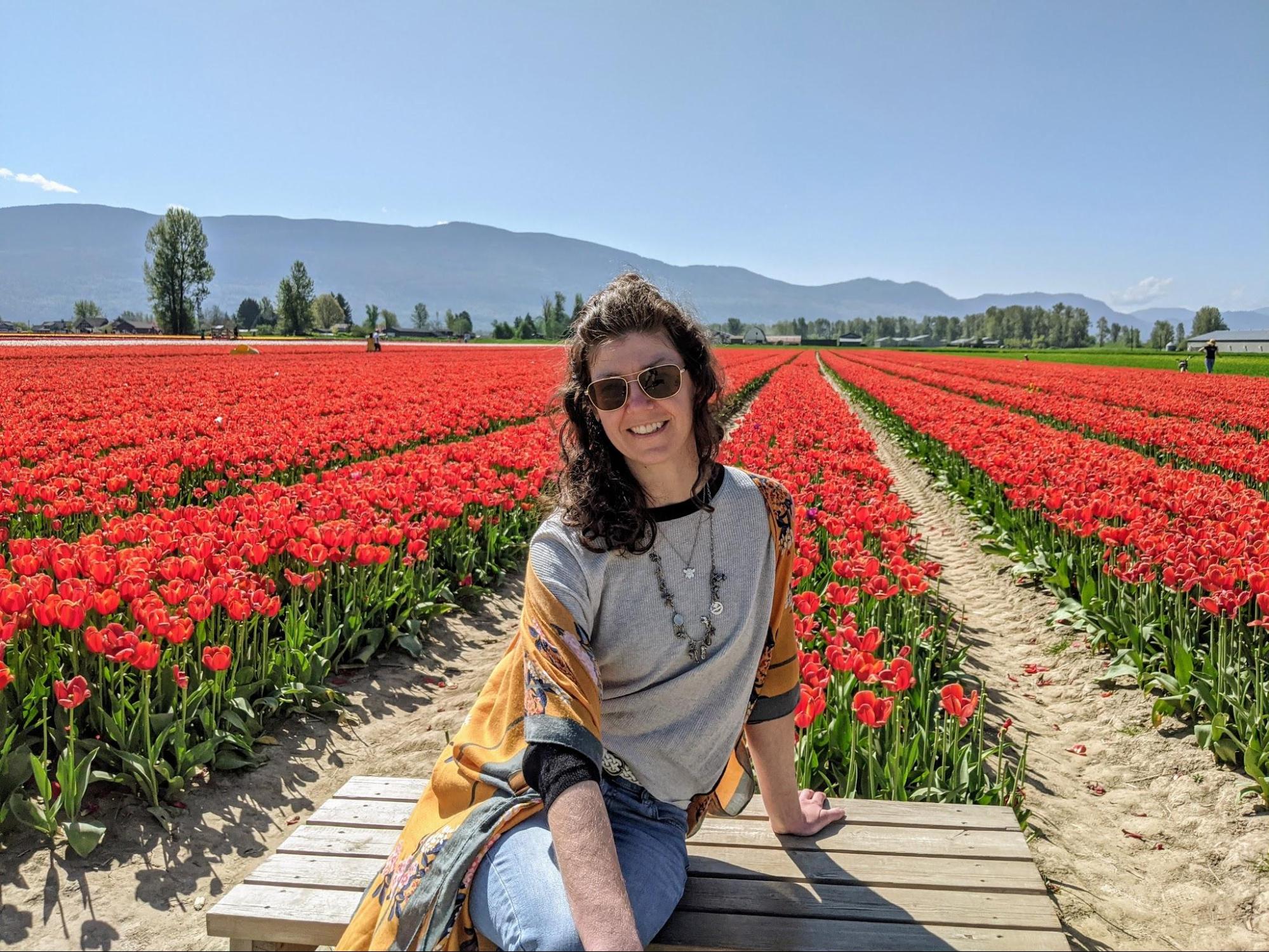 Mel sitting on a bench in a field of red tulips at the Chilliwack tulip festival