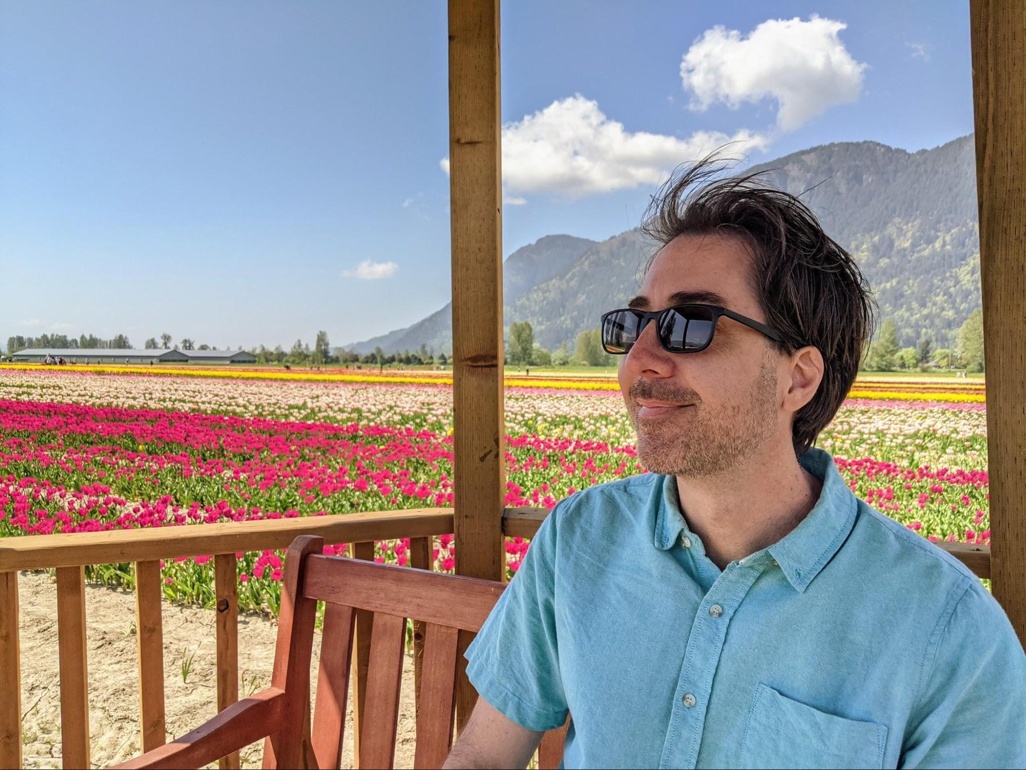 Jay sitting in a gazebo in front of the multi-colored field of tulips at the Chilliwack tulip festival 